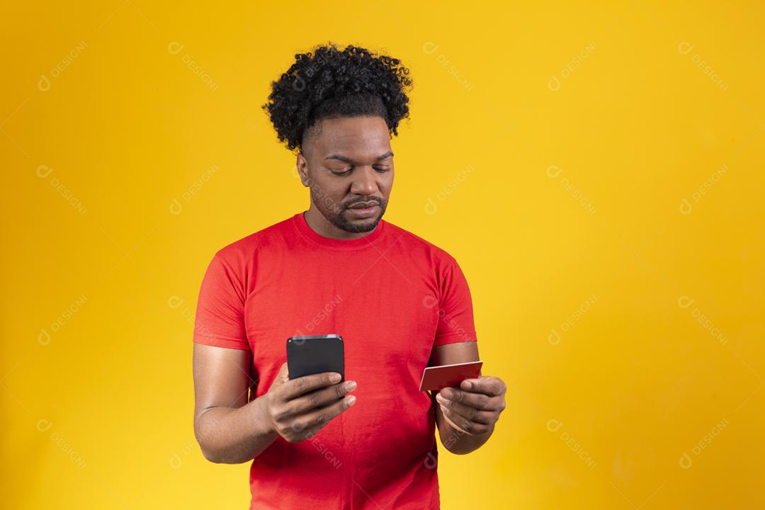 Alegre jovem afro segurando novo celular e um cartão de crédito