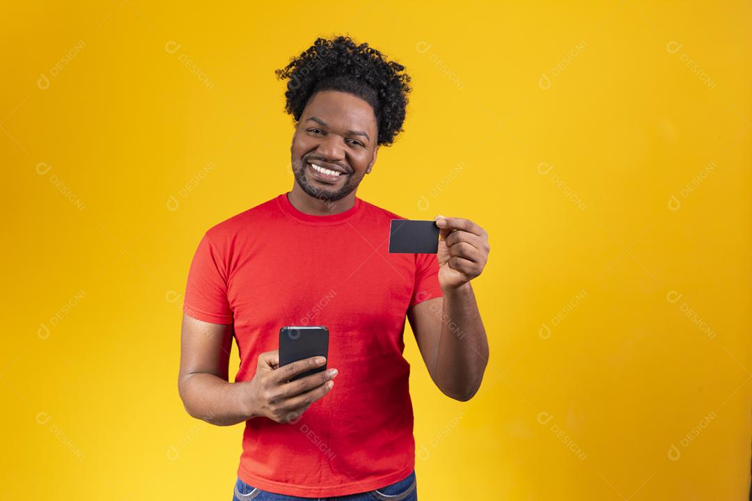Alegre jovem afro segurando novo celular e um cartão de crédito