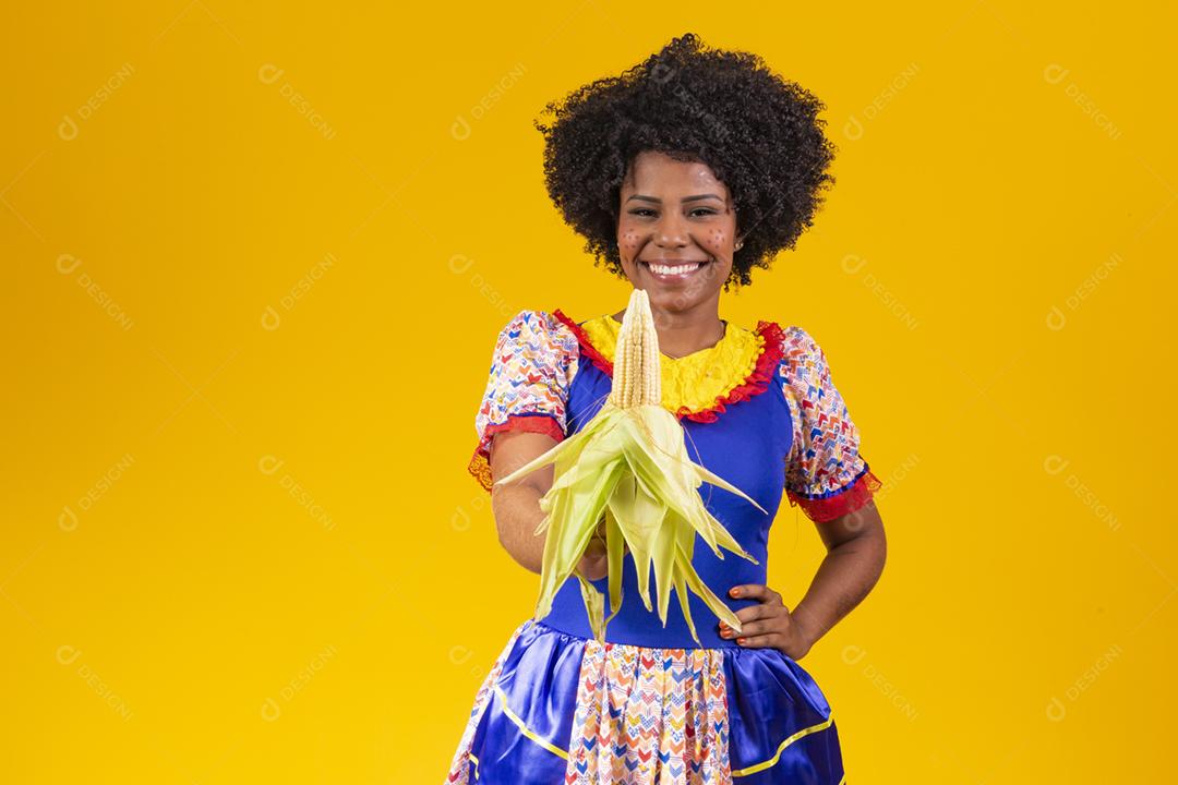 mulher bonita com roupas típicas da festa junina segurando um milho