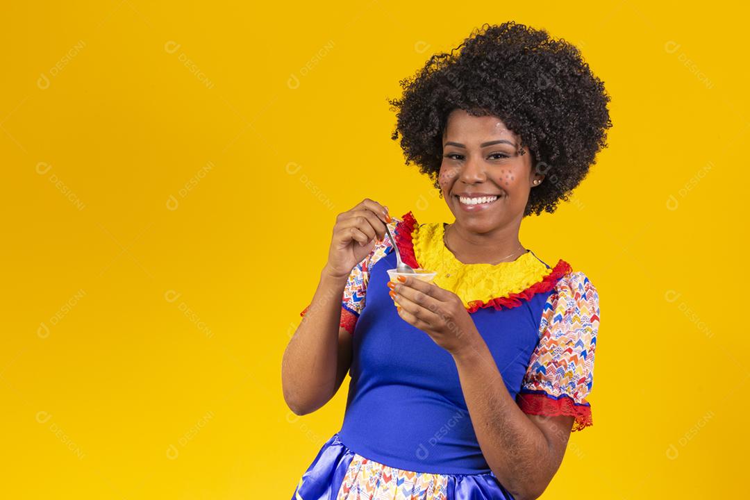 Afro woman dressed in June party clothes eating a delicious cural
