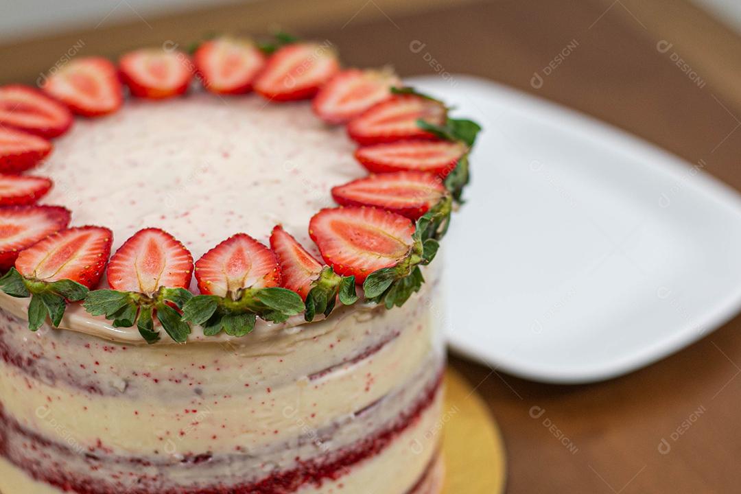Bolo recheado com chantili com morango acima de mesa de madeira