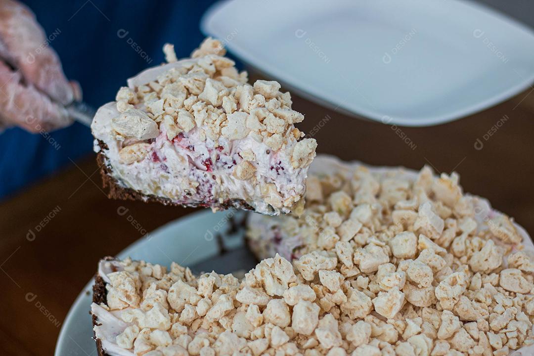 Pessoa cortando bolo de polvilho em cima de mesa de madeira