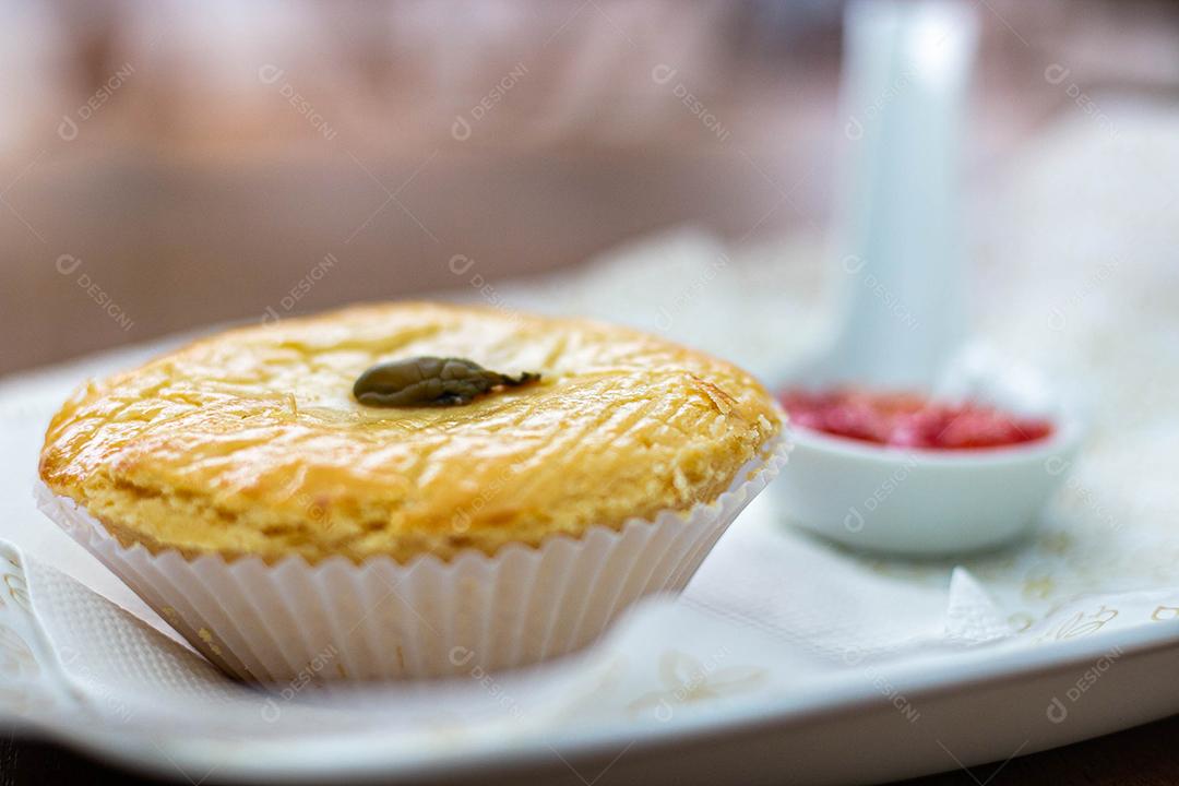Empadinha em prato branco com colher de temperos acima de mesa