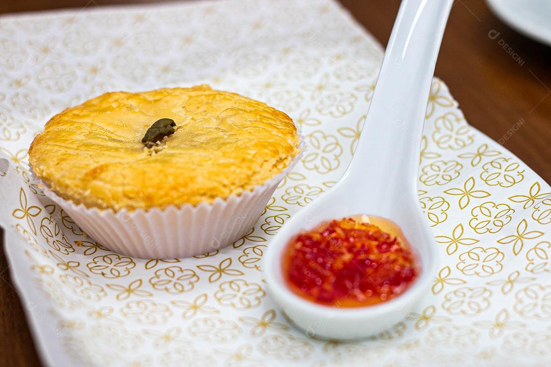 Empadinha em prato branco com colher de temperos acima de mesa