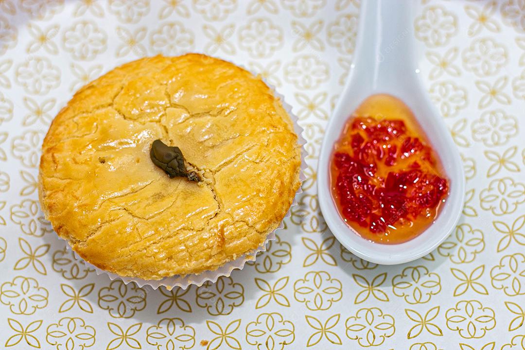 Empadinha em prato branco com colher de temperos acima de mesa