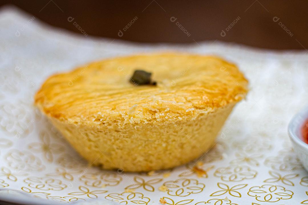 Empadinha em prato branco com colher de temperos acima de mesa