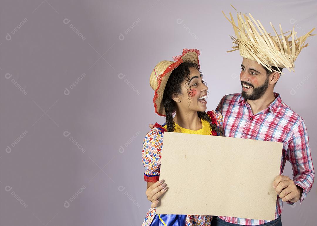 Brazilian couple wearing traditional clothes for Festa Junina and holding painting