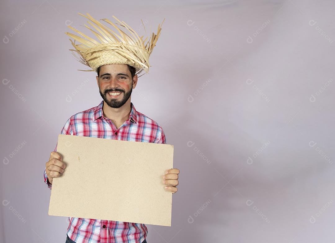 Homem brasileiro vestindo roupas típicas para Festa Junina e segurando quadro