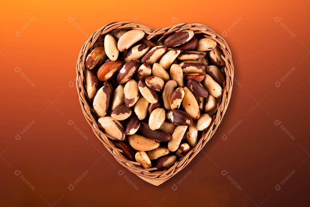 Castanha do Brasil na vista superior da cesta de coração com fundo gradiente colorido