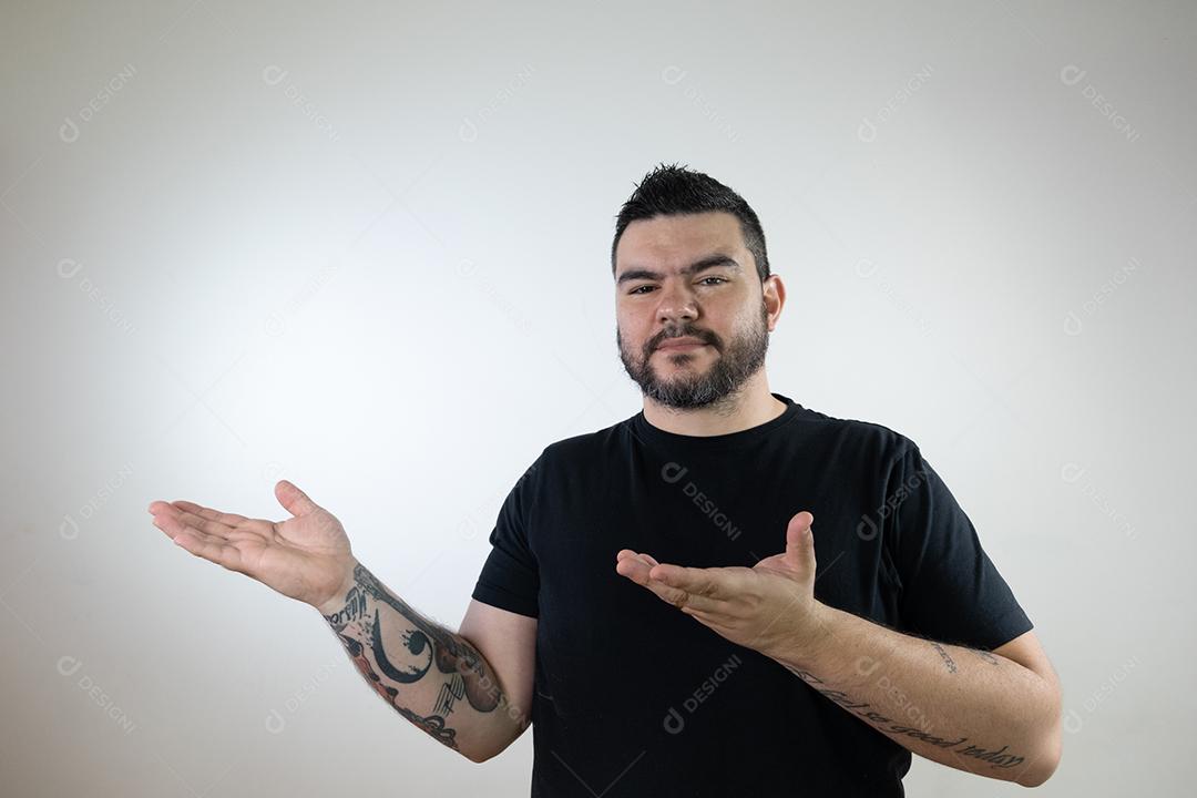 Homem moreno com camisa preta mostrando e apontando para a esquerda