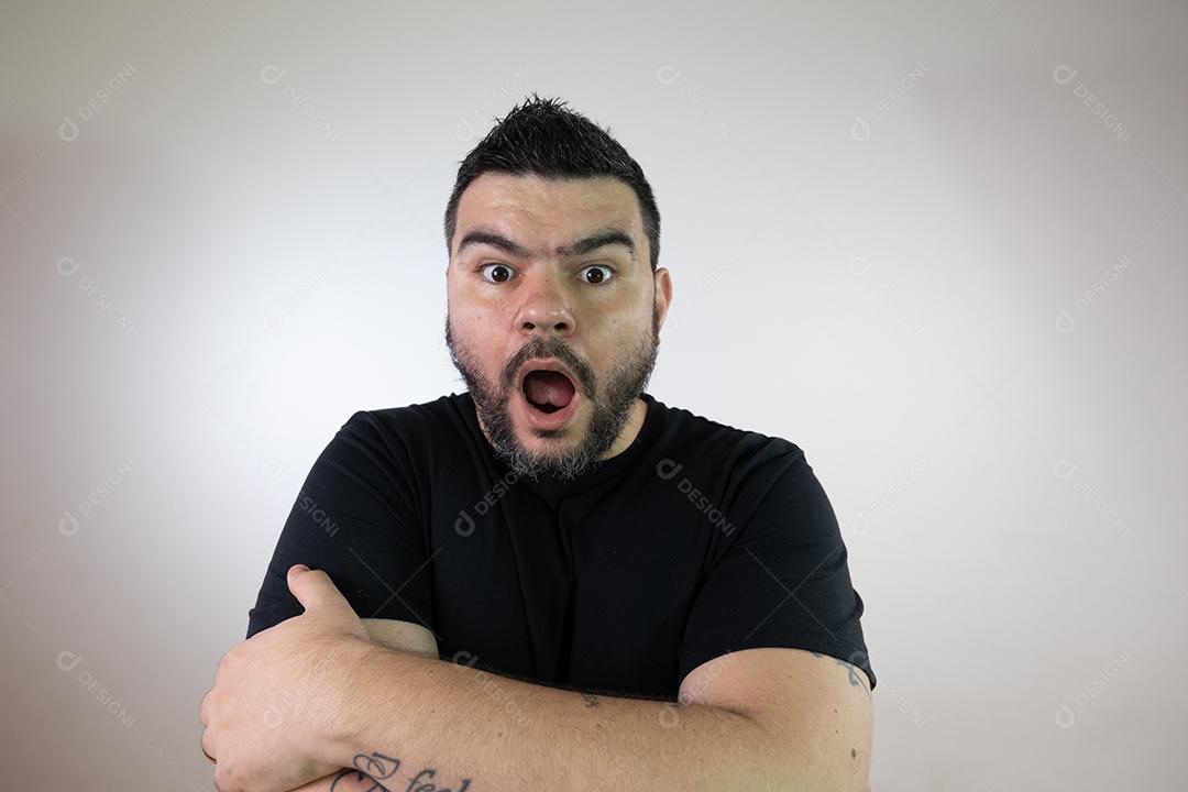 Homem moreno assustado em uma camisa preta em um fundo branco