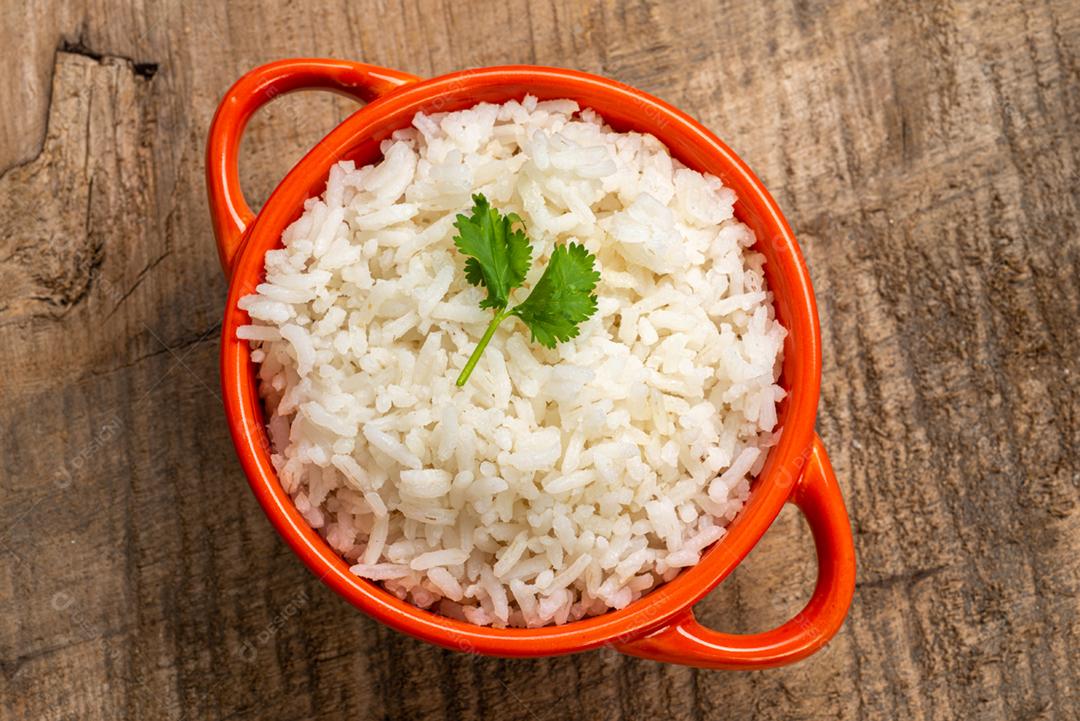 Arroz branco servido em uma tigela de barro em uma mesa de madeira rústica