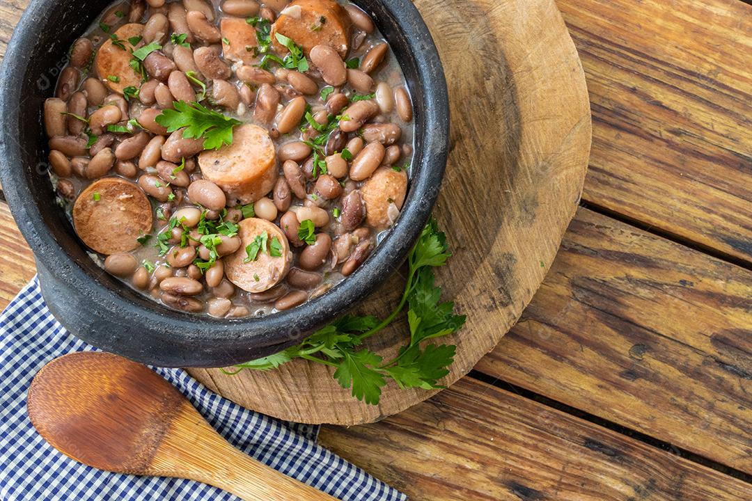 Panela de feijoada sobre mesa de madeira