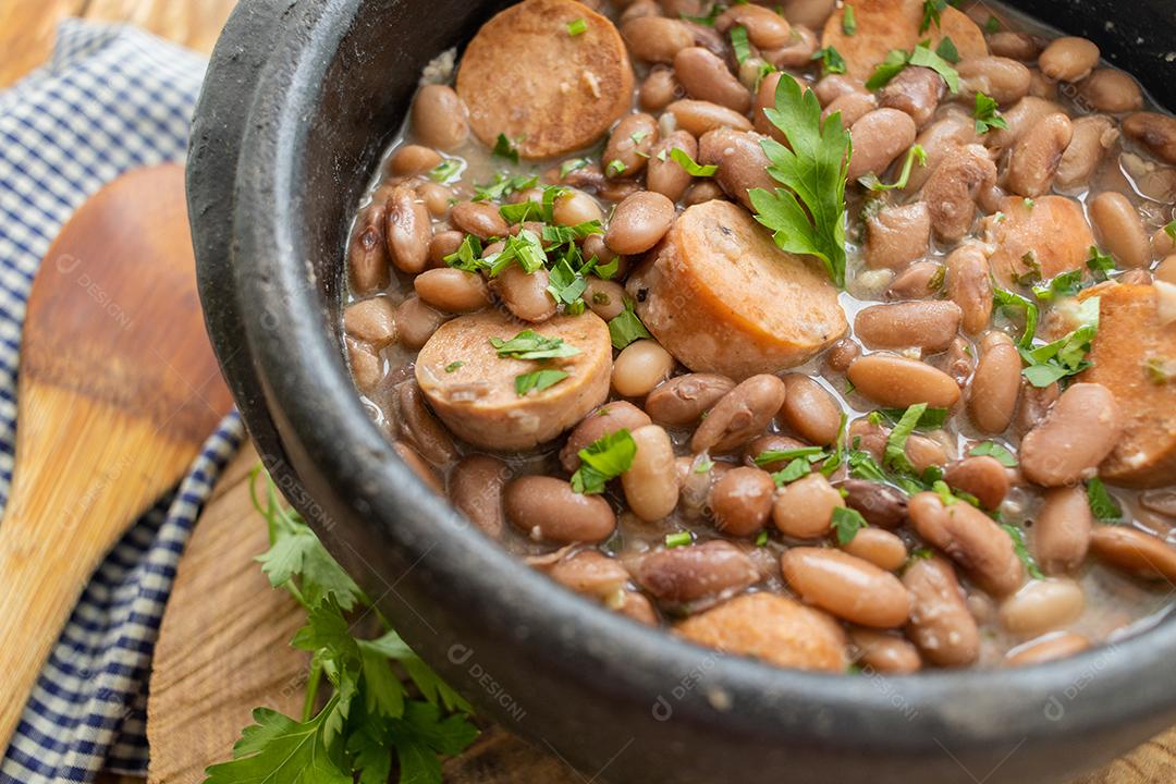 Panela de feijoada sobre mesa de madeira