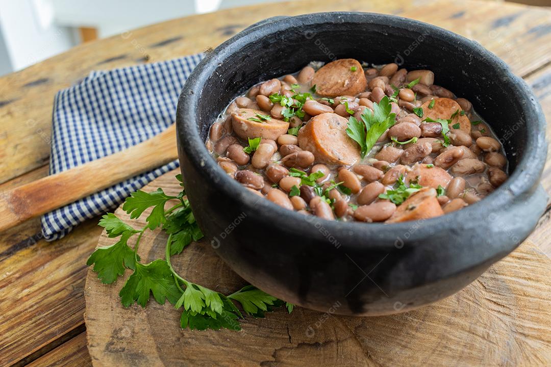 Panela de feijoada sobre mesa de madeira