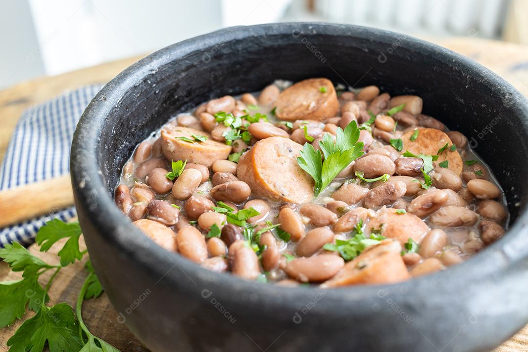 Panela de feijoada sobre mesa de madeira