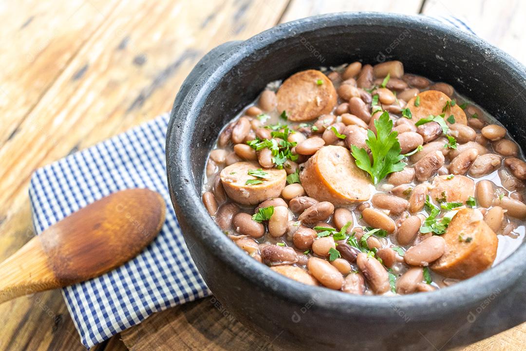 Panela de feijoada sobre mesa de madeira
