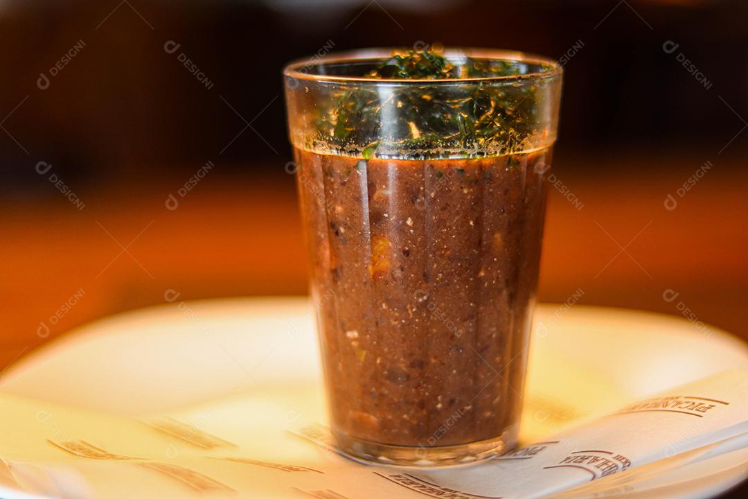 Copo de vidro com temperos e pimentas acima de prato