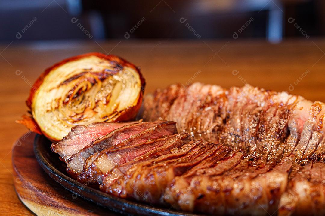 Tabua de madeira com carne mal passada e cebola