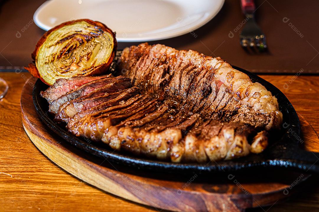 Tabua de madeira com carne mal passada e cebola