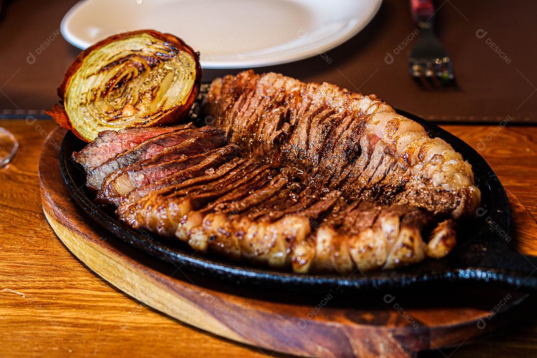 Tabua de madeira com carne mal passada e cebola