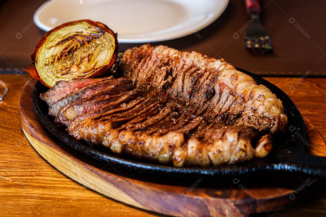 Tabua de madeira com carne mal passada e cebola