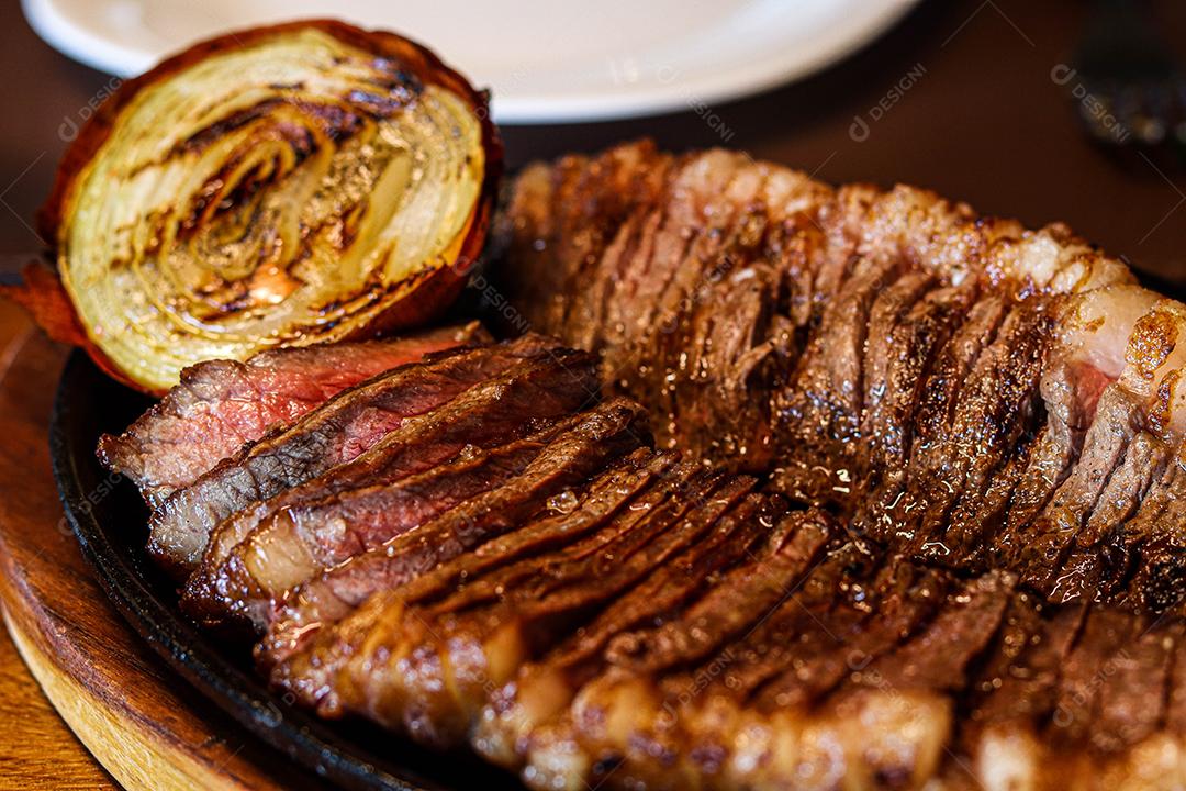 Tabua de madeira com carne mal passada e cebola