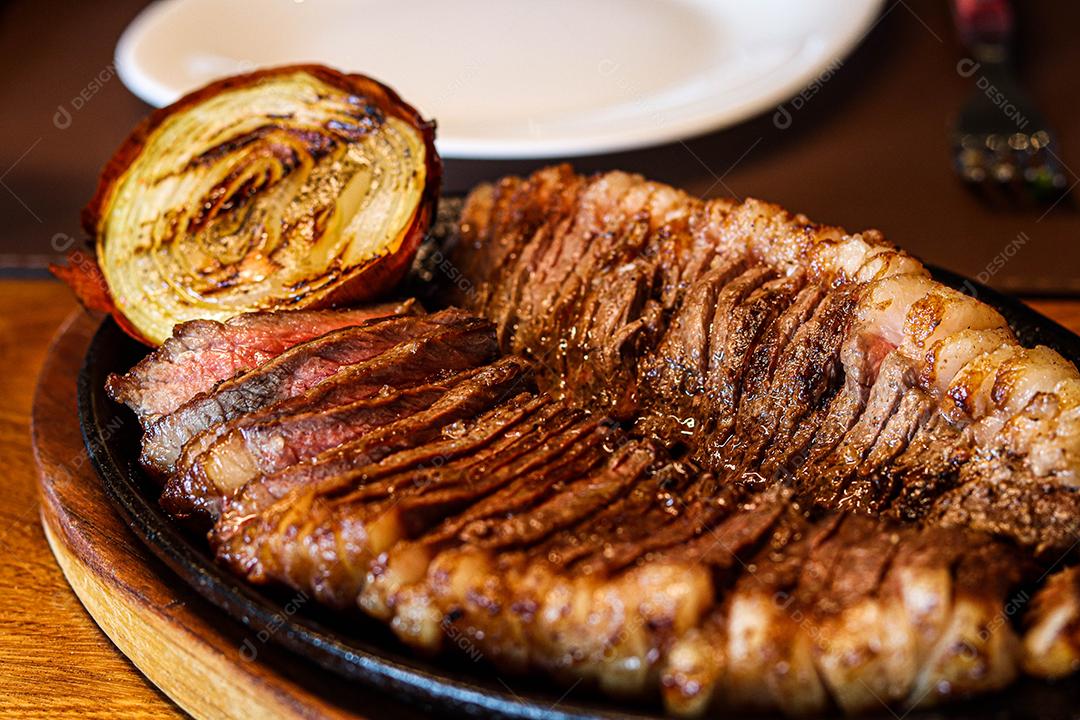 Tabua de madeira com carne mal passada e cebola