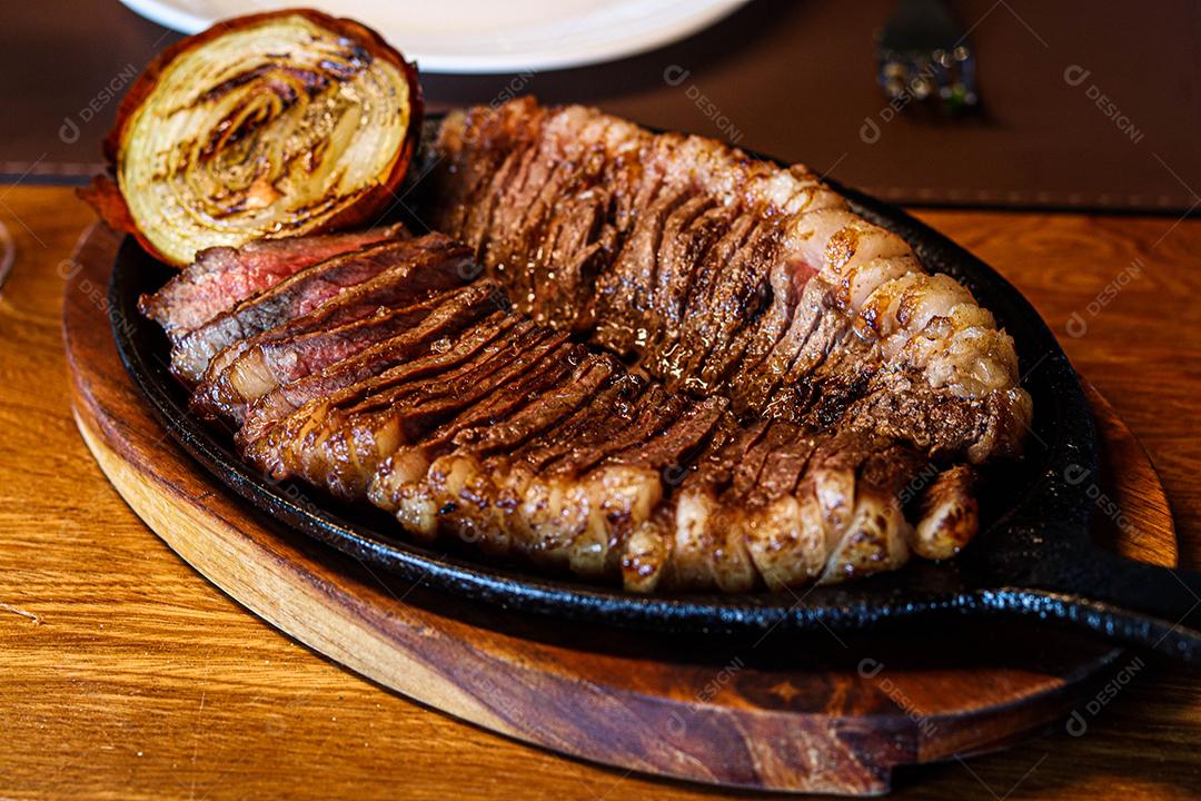 Tabua de madeira com carne mal passada e cebola