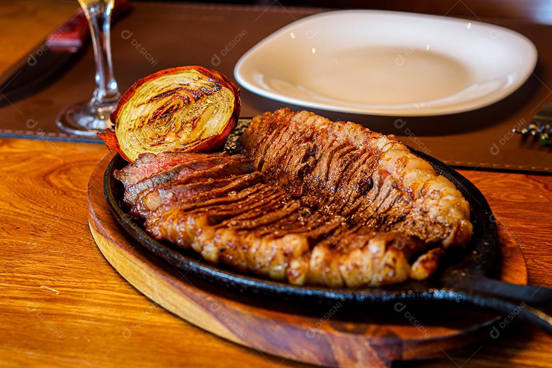 Tabua de madeira com carne mal passada e cebola