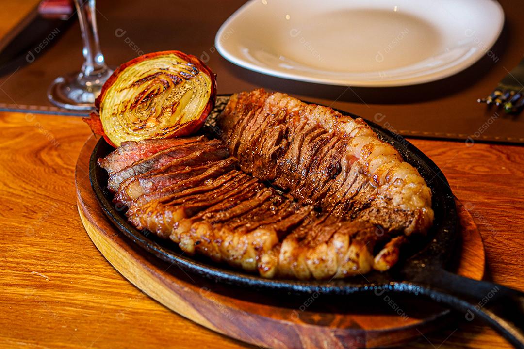 Tabua de madeira com carne mal passada e cebola