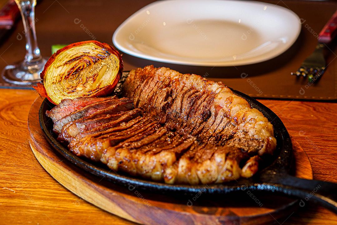 Tabua de madeira com carne mal passada e cebola