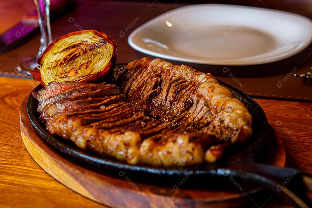 Tabua de madeira com carne mal passada e cebola