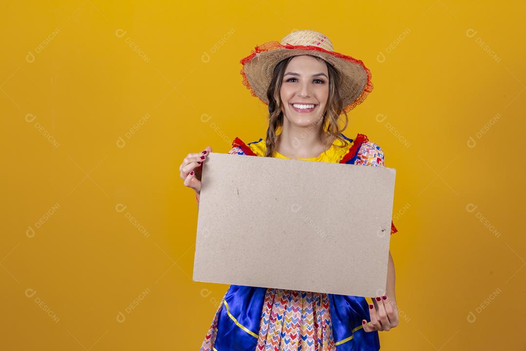 Linda mulher vestida com roupa de festa junina segurando um quadro em branco