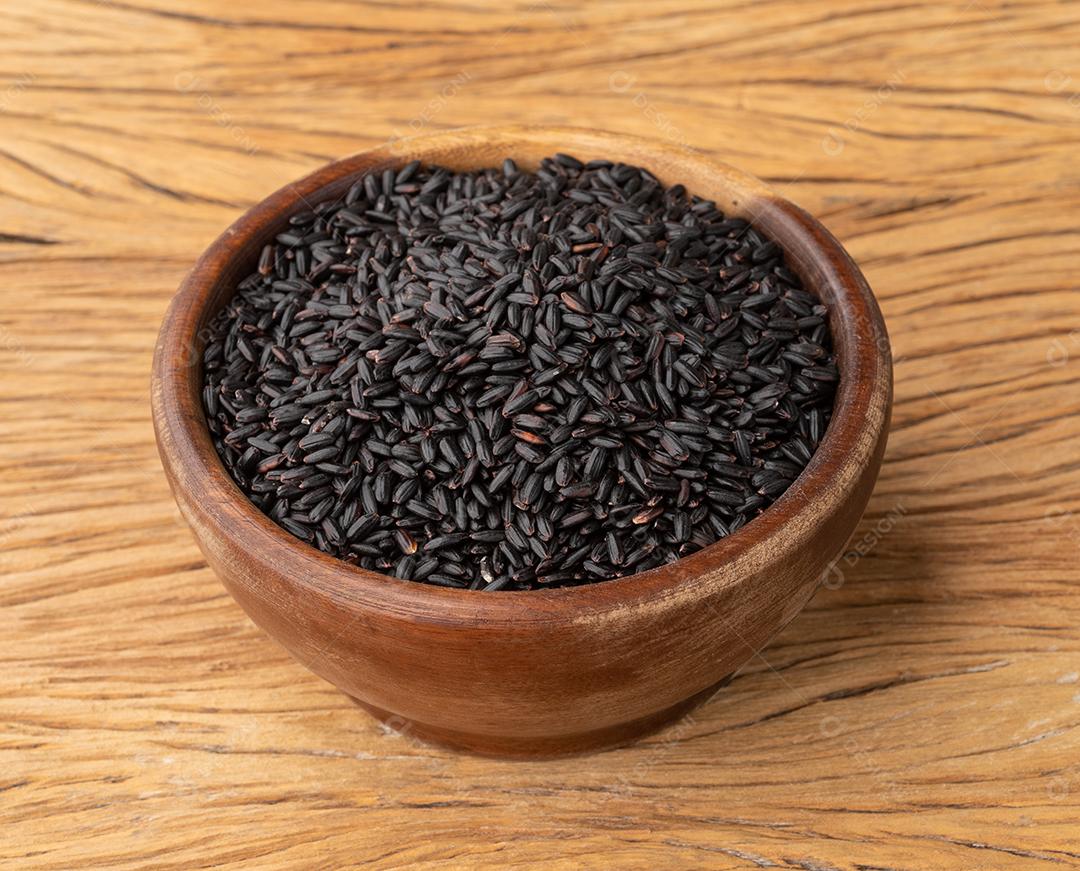 Arroz preto cru em uma tigela sobre a mesa de madeira.