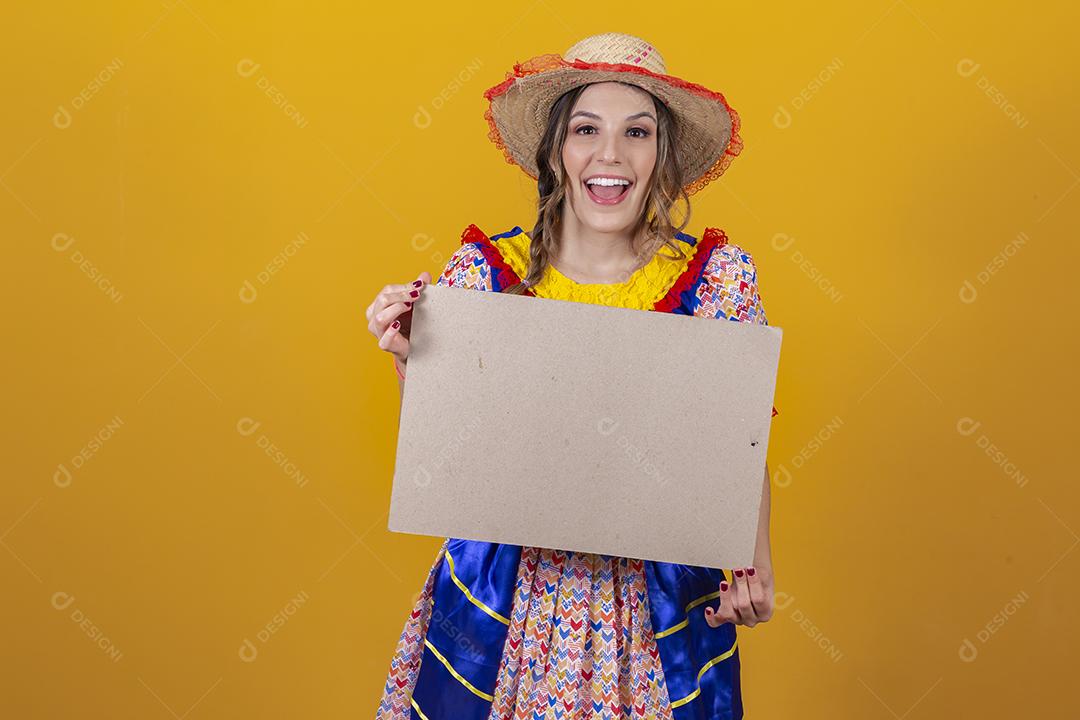 Linda mulher vestida com roupa de festa junina segurando um s em branco