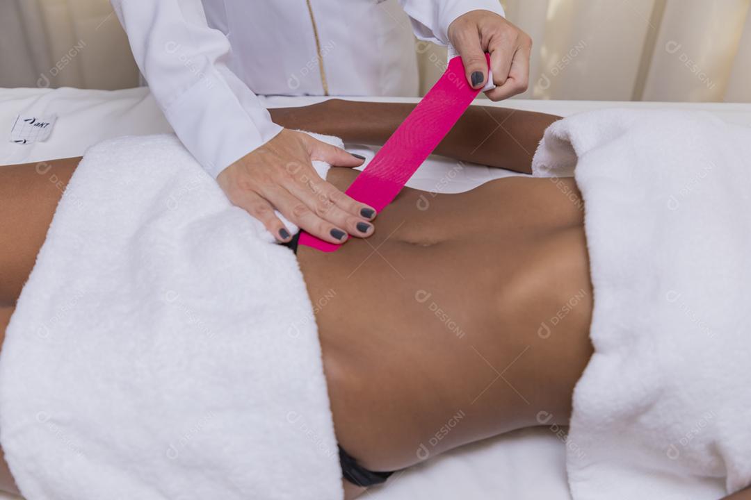 Fisioterapeuta usando Kinesio Tapping na barriga do paciente