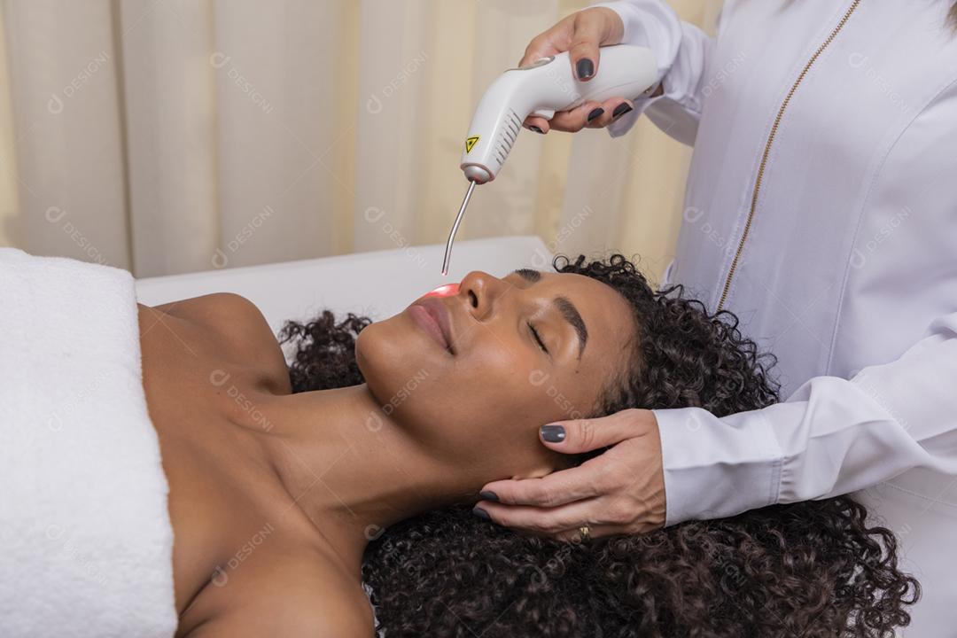 Mulher usando laser em clínica estética para cicatriz facial