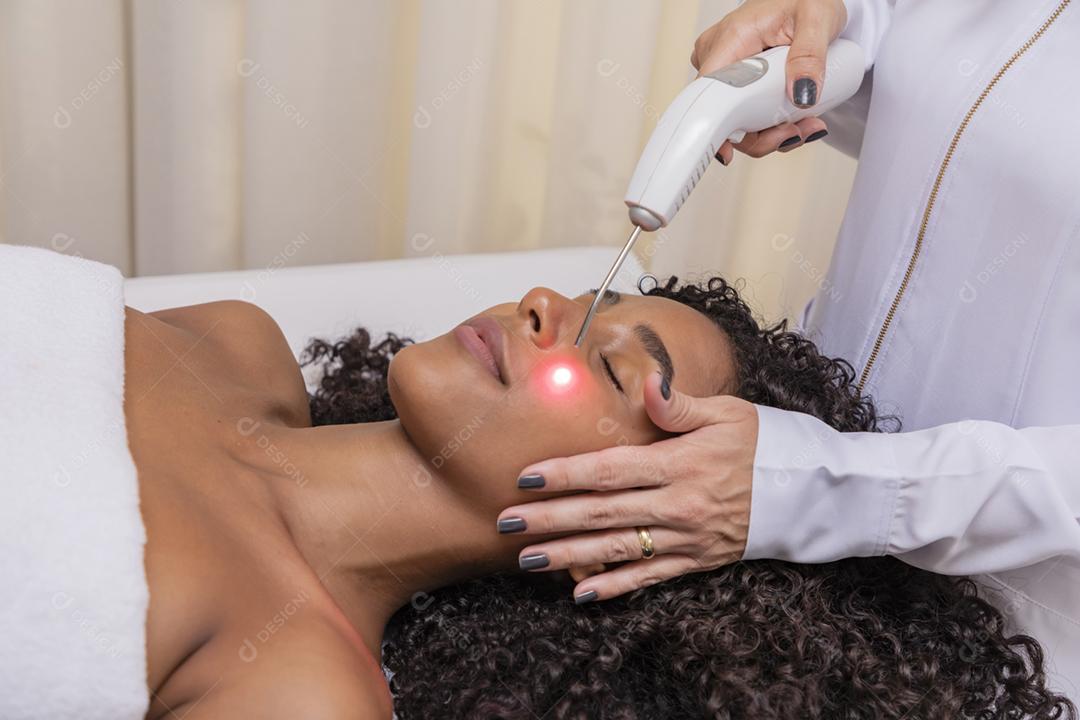 Mulher usando laser em clínica estética para cicatriz facial