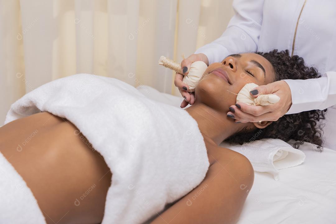 mulher recebendo massagem facial com pindas chinesas
