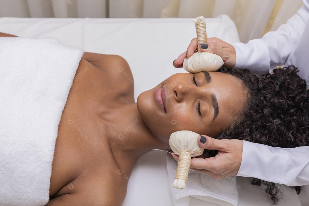 mulher recebendo massagem facial com pindas chinesas