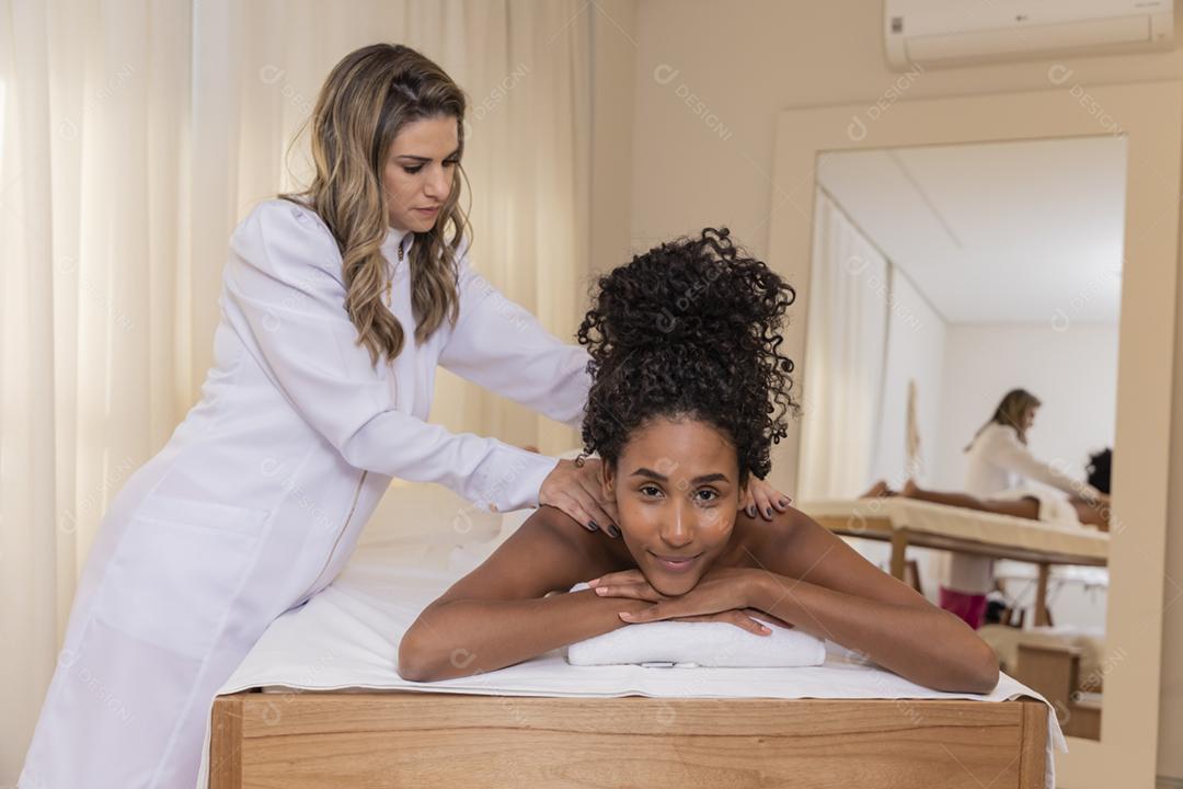 Mulher negra recebendo massagem no spa.