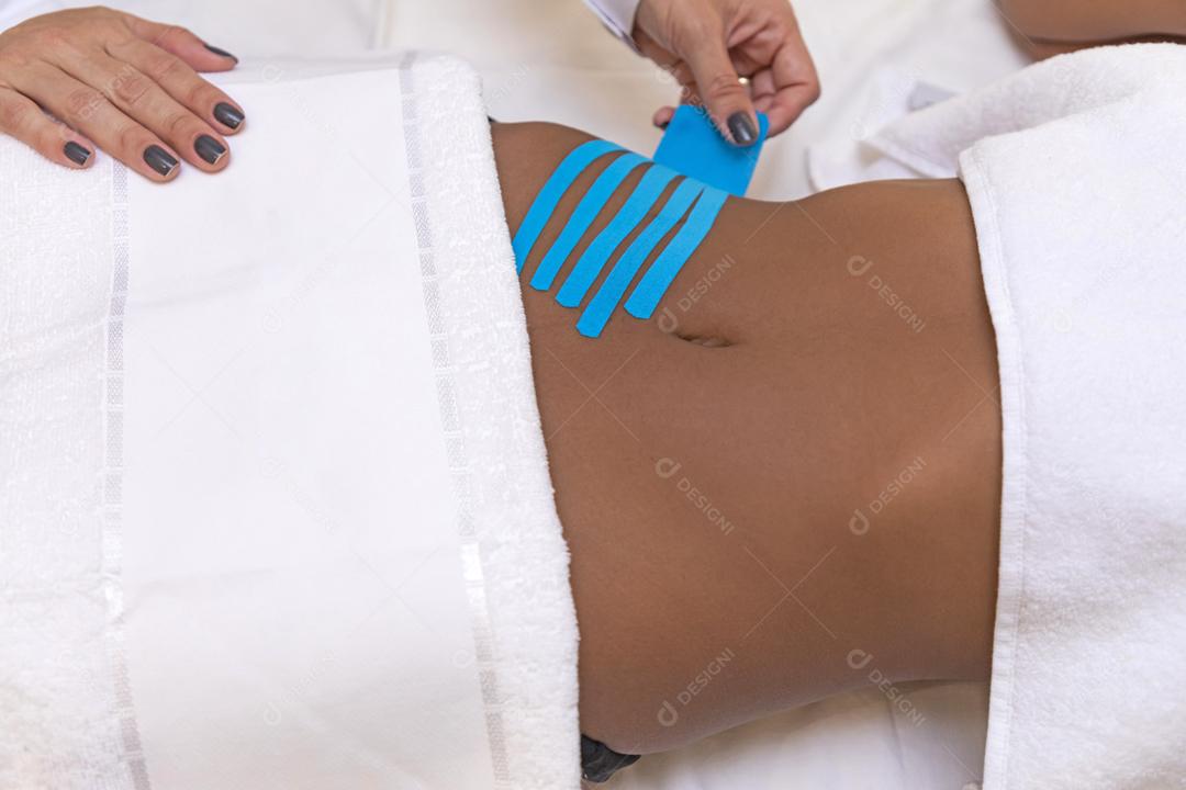 Fisioterapeuta usando Kinesio Tapping na barriga do paciente