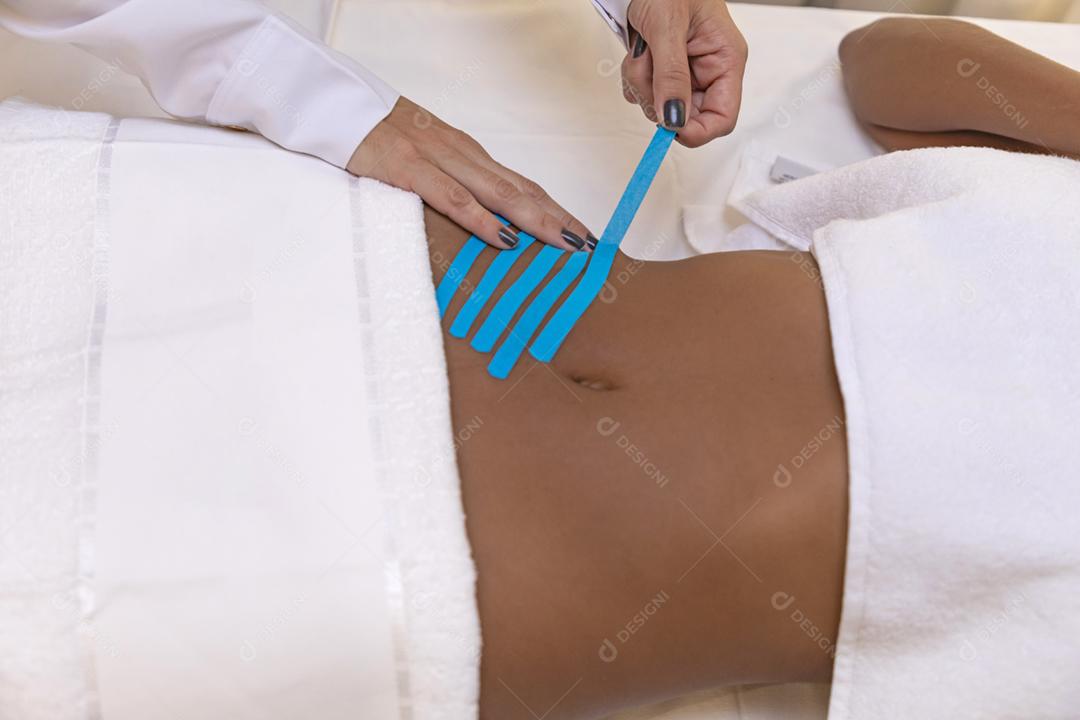 Fisioterapeuta usando Kinesio Tapping na barriga do paciente