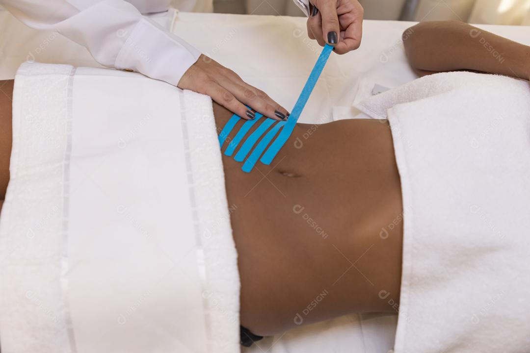 Fisioterapeuta usando Kinesio Tapping na barriga do paciente