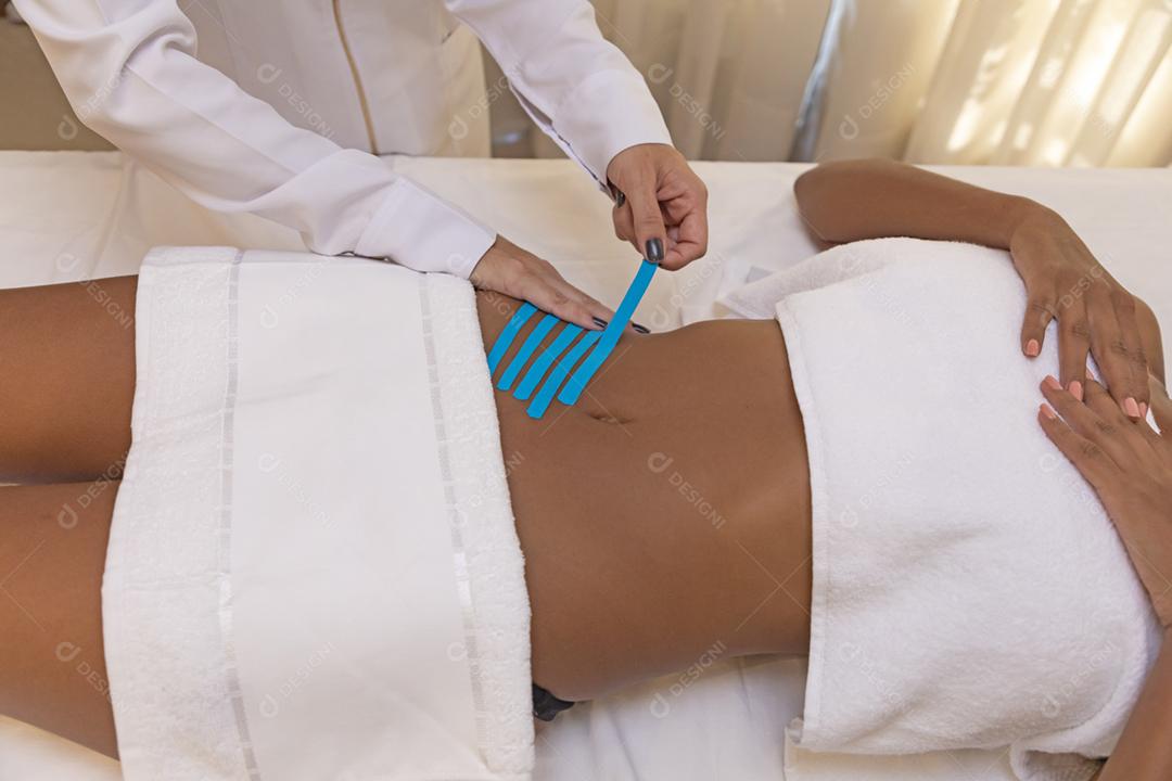 Fisioterapeuta usando Kinesio Tapping na barriga do paciente