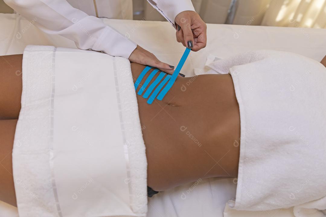Fisioterapeuta usando Kinesio Tapping na barriga do paciente