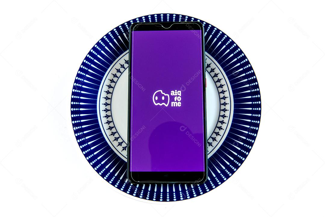 Aplicativo Aiqfome na tela do smartphone dentro do prato vazio. Ijuí, Brasil