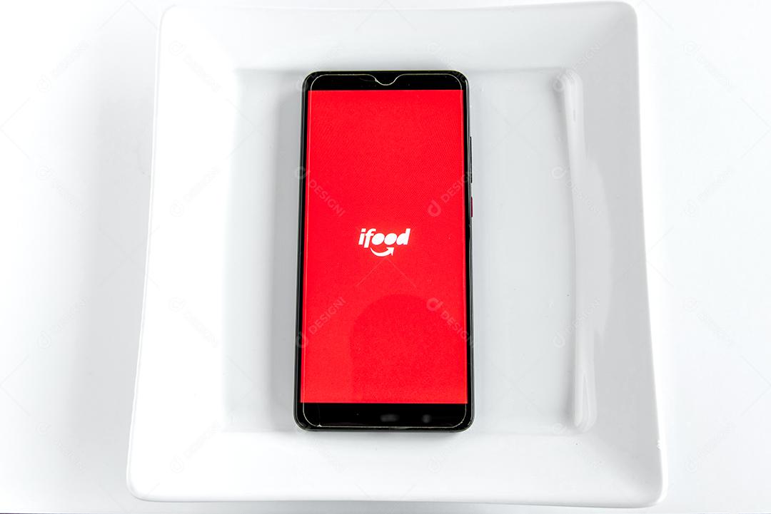 Aplicativo Ifood na tela do smartphone dentro do prato vazio. Ijuí, Brasil