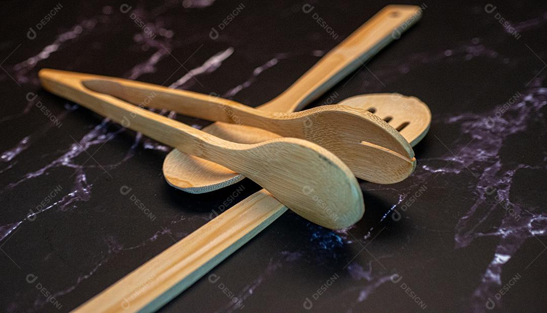 Colheres de madeira em uma mesa de mármore preta.